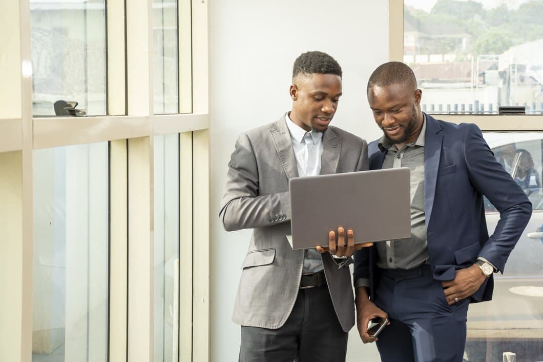 Two men having a conversation with one holding a laptop