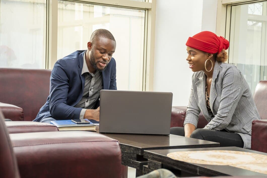 man and lady in a room having a conversation and looking into a laptop